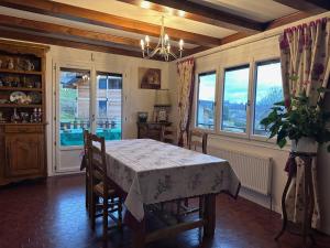 a dining room with a table and some windows at Le chalet st hubert in Montcel