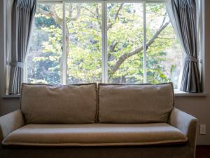 a couch sitting in front of a large window at バケーションイン伊豆高原 in Ito