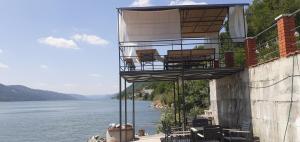 a balcony on the side of a building next to the water at Cazanele Dunarii "La Cumatru" in Dubova