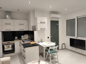 a kitchen with white cabinets and a table with a chair at Corfu Nature Suites in Corfu +1 photo