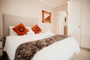 a bedroom with a white bed with orange pillows at Megs Guesthouse in Ballito