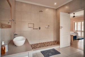 a bathroom with a tub and a shower with a sink at Megs Guesthouse in Ballito +102 photos