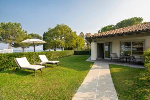 a patio with chairs and an umbrella in a yard at Splendido Bay Luxury Spa Resort in Padenghe sul Garda