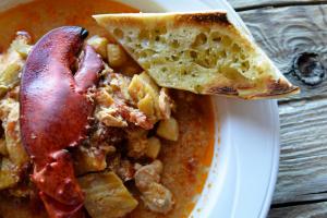 a plate of food with a slice of pizza and stew at Riotel Perce in Perce
