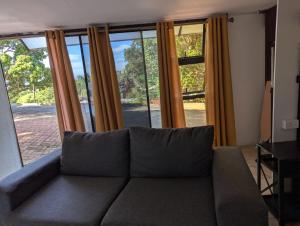 a couch sitting in a living room with windows at Carravensiria Chalet 27 in Hibberdene