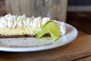 a slice of cheesecake with a lime on a plate at Riotel Perce in Perce