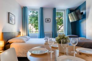 a room with a bed and a table with wine glasses at Blue Bird - Logement sur les Ramblas in Toulouse +7 photos