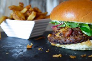 a hamburger and fries with a basket of fries at Riotel Perce in Perce