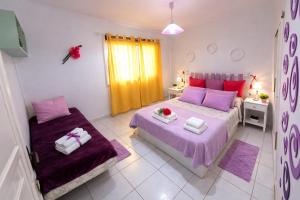 a bedroom with two beds with purple and pink pillows at Sunny Pool Apartment Costa del Silencio in Arona