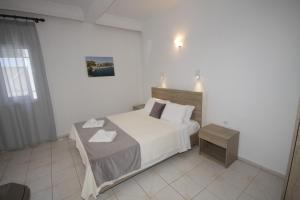 a white bedroom with a bed and a table at PortoDream Studios & Apartments in Neos Marmaras