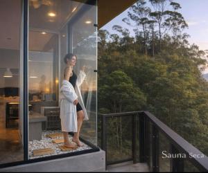 a woman standing on the balcony of a house at Chalé Boutique - Spa - Sauna seca , Jacuzzi , Rede suspensa in Campos do Jordão