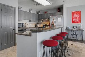 a kitchen with red stools at a counter at Shop & Dine: Fort Worth Condo w/ Racetrack Views! in Fort Worth