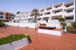 a large white apartment building with a brick courtyard at Sunny Pool Apartment Costa del Silencio in Arona