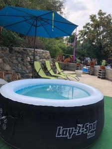 a large hot tub with an umbrella and chairs at Görbe Vendégház in Tarcal