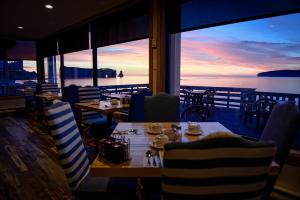 a restaurant with tables and chairs with a view of the ocean at Riotel Perce in Perce