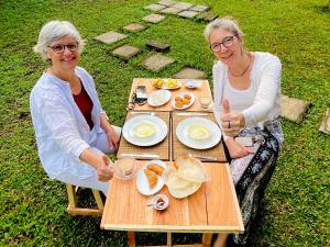 two women sitting at a table with food on it at Sigiriya Lahiru Homestay in Sigiriya