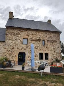 a stone house with a patio and a blue umbrella at Gîte coup de cœur in Pluvigner