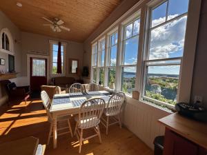 a dining room with a table and chairs and windows at Trinity's Oceanview Gem 2BR St Paul's Schoolhouse in Trinity +27 photos