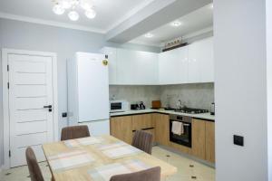a kitchen with a wooden table and a kitchen with white cabinets at Apartaments Parking Taxi in Chişinău