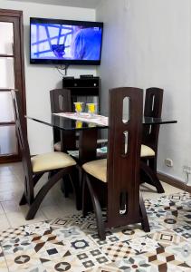 a dining room table and chairs with a television on a wall at Tu Estancia en Cali - Valle del Lili in Cali