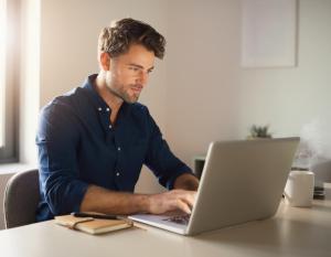 a man sitting at a table using a laptop computer at Appartement Borger mit Garten in Sauerlach