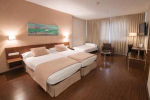 a hotel room with two beds and a desk at ARVA Abad San Antonio in León