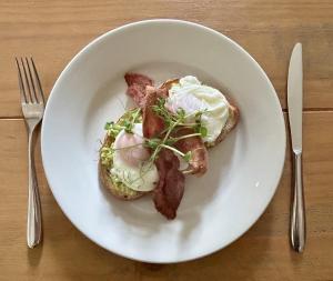 a plate of food with bacon and eggs on a table at Penryn House Hotel in Polperro