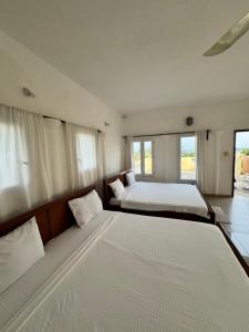 a large bedroom with a large bed and windows at Ramaya Auberge Espagnole in Grand-Popo