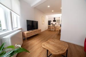 a living room with a flat screen tv and a stool at Sarridal, Lar Atlántico in Cedeira
