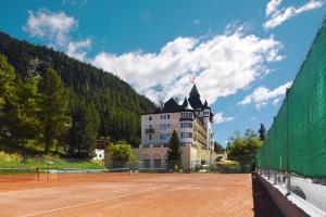 a building on a tennis court with a tennis court at Hotel Walther - Relais & Châteaux in Pontresina