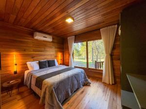 a bedroom with a bed and a large window at Villa Vida Cabanas in São Joaquim