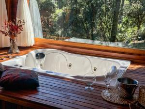 a bath tub sitting in a window with two wine glasses at Villa Vida Cabanas in São Joaquim