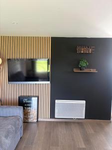 a living room with a black wall with a tv at Chambre d'Hôtes Arla Goxoki in Amendeuix-Oneix