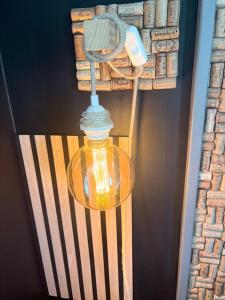 a glass light hanging from a wall with a mirror at Chambre d'Hôtes Arla Goxoki in Amendeuix-Oneix