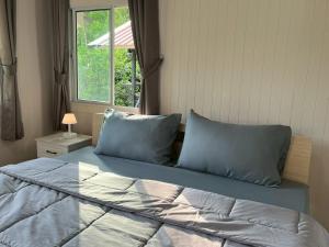 a bedroom with a bed with blue pillows and a window at Wildnest House in Ko Yao Noi