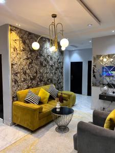 a living room with a yellow couch and a stone wall at Executive 2-Bedroom Apartment in Ikeja