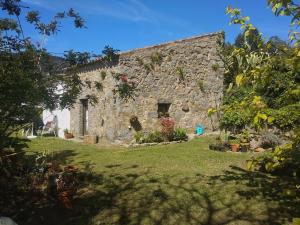 an old stone building with flowers in a yard at Casa Branca AL in Monchique