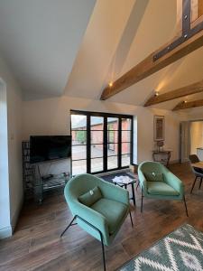 a living room with two green chairs and a tv at Knowle Grange Guest House in Frant