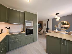 a kitchen with green cabinets and a living room at La fleur des eaux de Beauval in Noyers-sur-Cher +18 photos