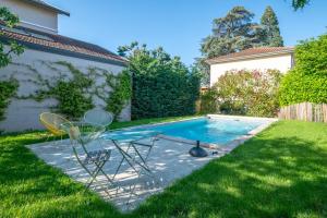 a pool with two chairs and a table in the grass at Villa Mont d'or - Welkeys in Champagne-au-Mont-dʼOr