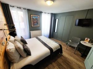 a bedroom with a bed and a table and a chair at Le Grand Hotel in Barcelonnette