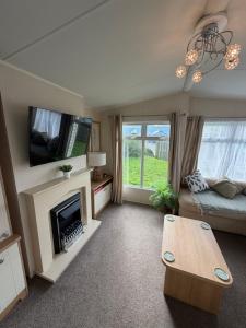 a living room with a fireplace and a table at Sunshine Newquay Bay Resort in Newquay Bay Resort