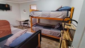 a dorm room with two bunk beds and a table at EL ROBLE 2 CHILLaN in Chillán