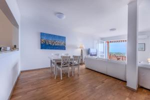 a white living room with a table and a dining room at Capo d'Arco - Quadrilocale Le Mimose in Capo D'Arco