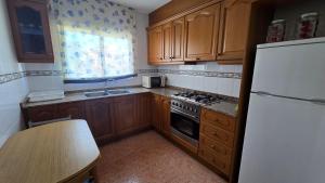 a kitchen with wooden cabinets and a white refrigerator at Chalet Kabesa Peñiscola in Peniscola