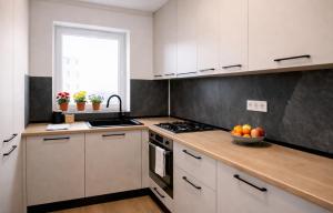 a kitchen with white cabinets and a bowl of fruit on the counter at LUMO Terrace Studio with Private Parking near Coresi in Braşov +15 photos
