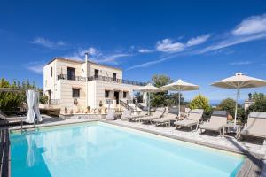 a pool with chairs and umbrellas in front of a house at Villa Rosemary - Luxury Nature Escape in Roussospítion