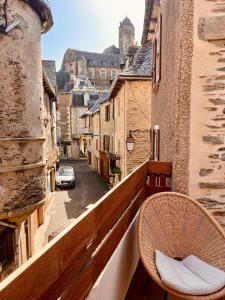 a chair on a balcony with a view of a street at la grange d'Eugenie in Estaing
