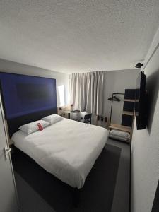 a bedroom with a large white bed with a blue headboard at Hotel ibis Autun in Autun +71 photos