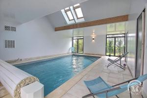 a swimming pool in a house with a ceiling at Le val d'ic in Pordic
